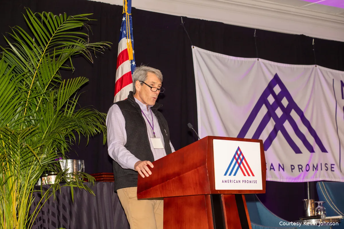 Man at a podium with American Promise logo