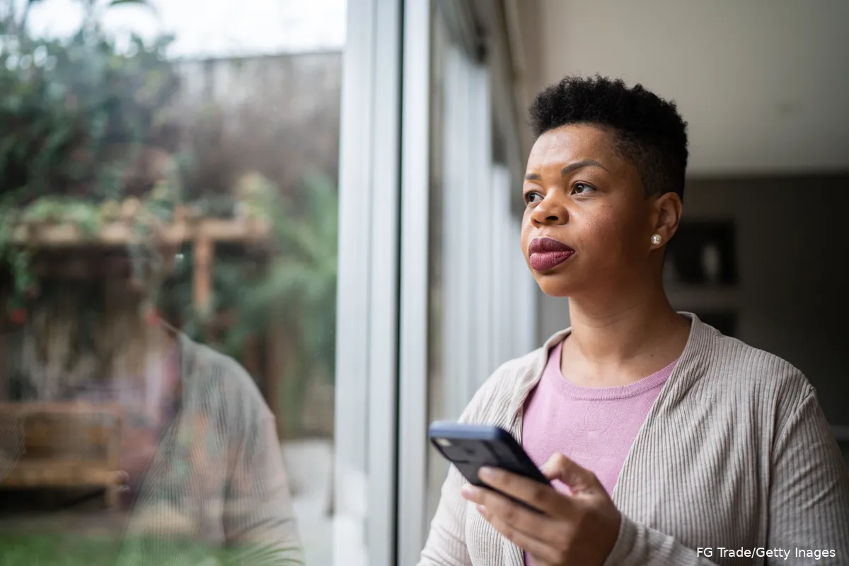 Woman looking off into the distance while holding her mobile phone