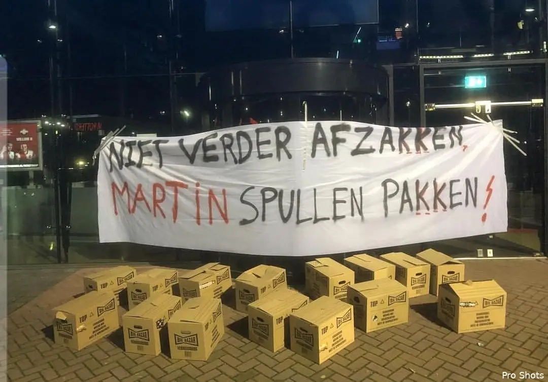 Verhuisdozen en spandoek bij Maasgebouw tegen Van Geel