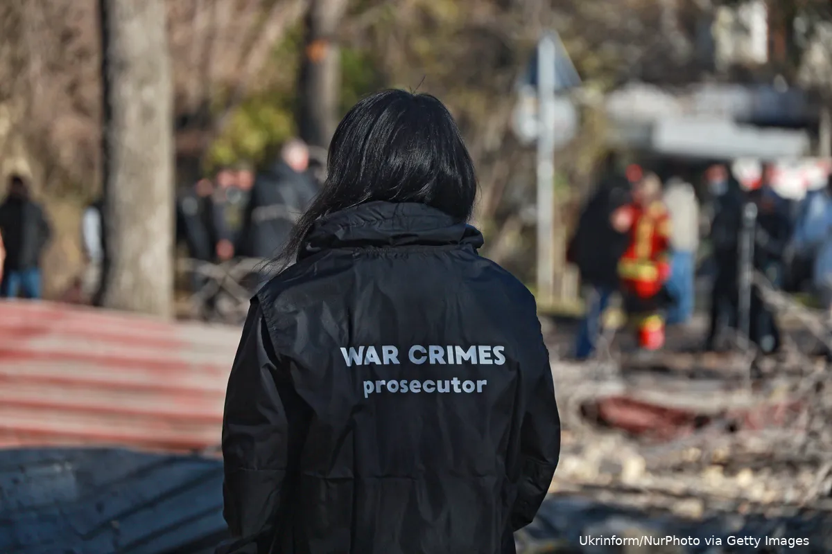 Person i jacket that reads "War Crimes prosecutor"