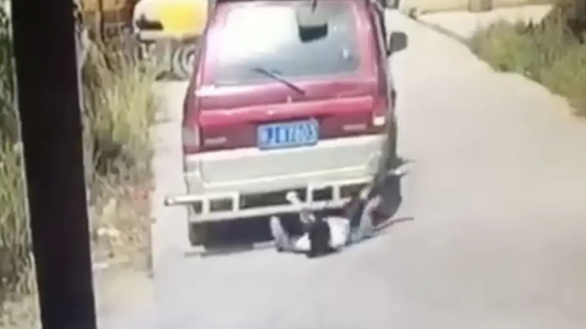 Dame kijkt op telefoon en komt onder busje terecht