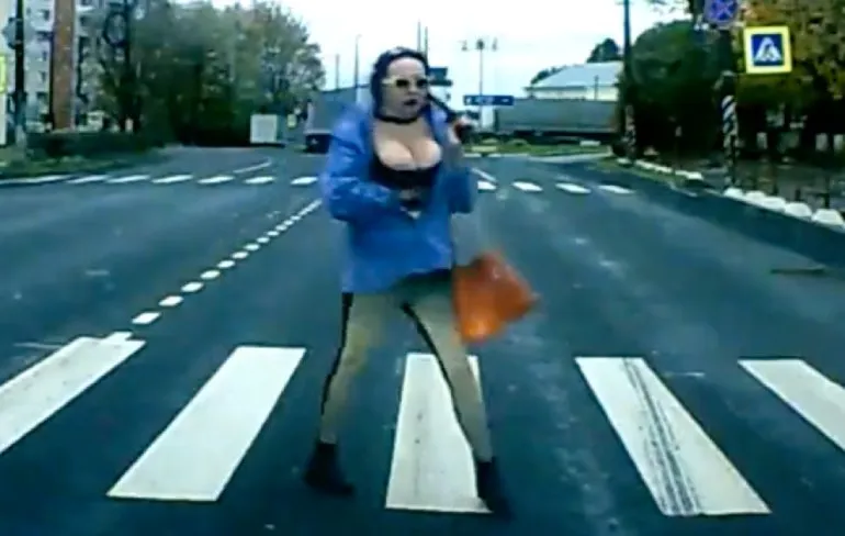 Dame gaat op jolige wijze het zebrapad over