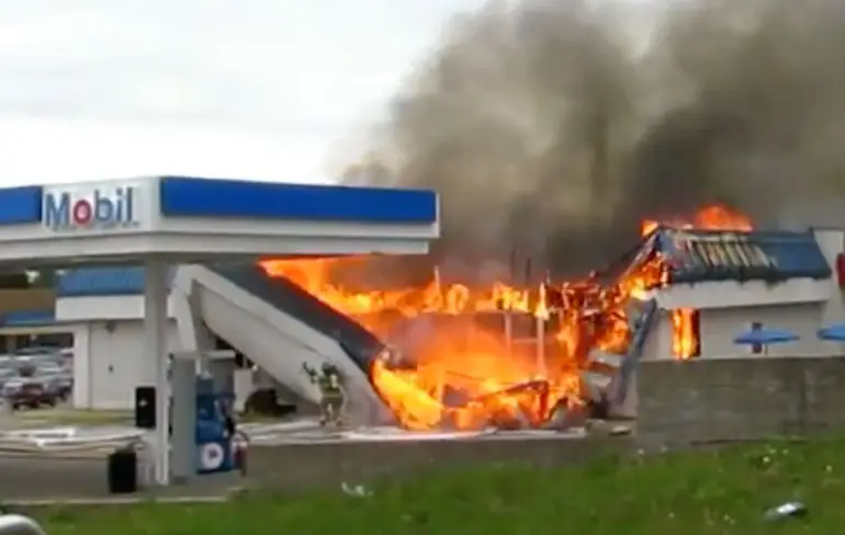 Voorzijde van brandende benzinepomp valt op brandweerman