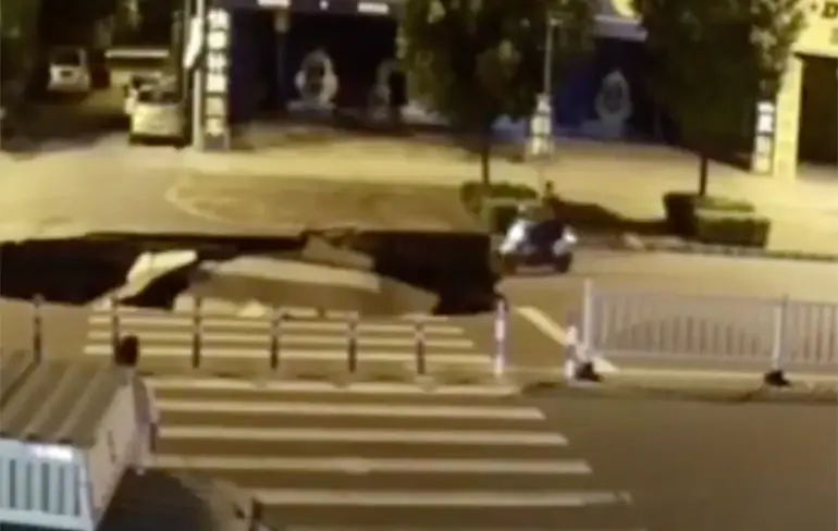 Bellende Chinees op scooter ziet sinkhole over het hoofd