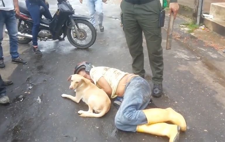 Dronken man slaapt roes uit op straat en zijn hondje waakt over hem