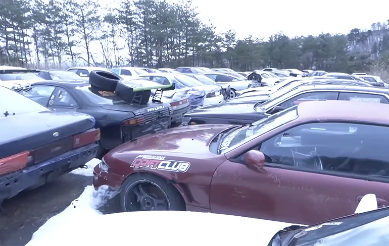 Een kijkje op een soort van kerkhof waar drift auto's staan