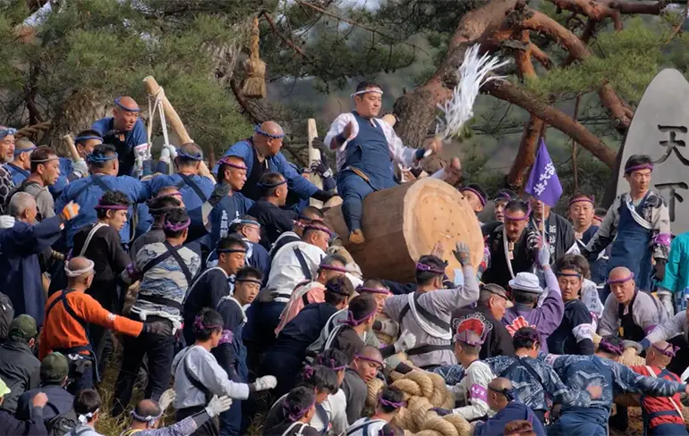 Japanners glijden op boomstam naar beneden op Onbashira festival
