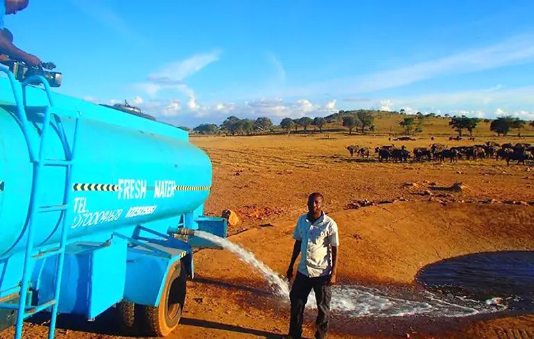Man in Kenia geeft dorstige dieren water