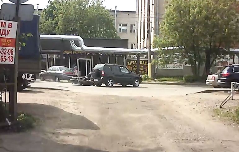 Motorrijder in Rusland komt onder auto vast te zitten