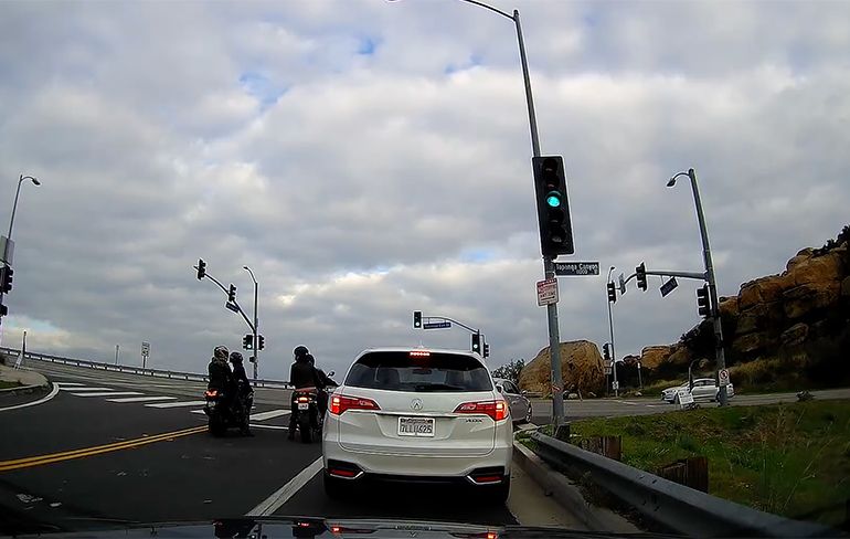 Motorrijder met passagier vallen om bij stoplicht