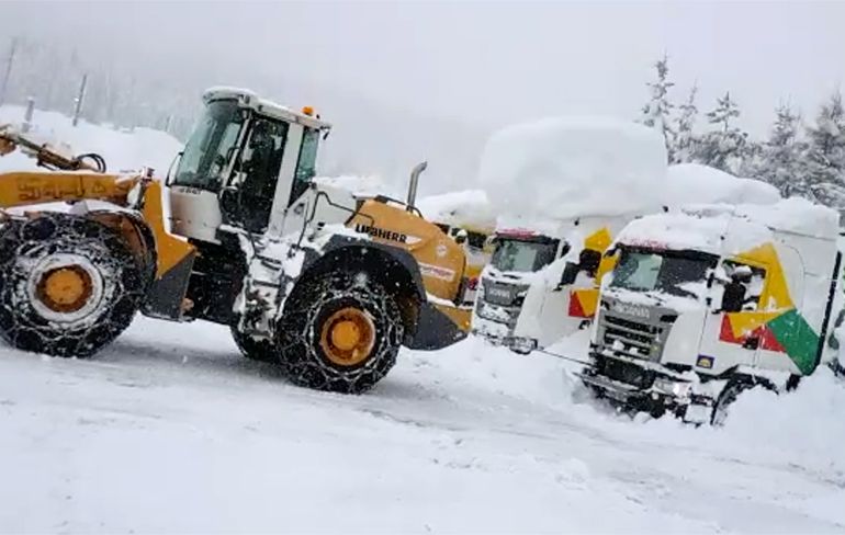 Ondergesneeuwde vrachtwagen wordt uit de sneeuw getrokken