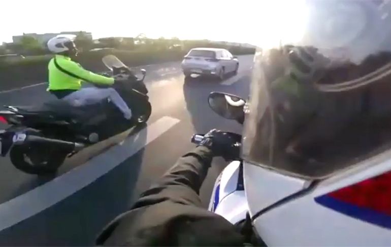 Politie op motor zit achter motorscooter aan op de snelweg