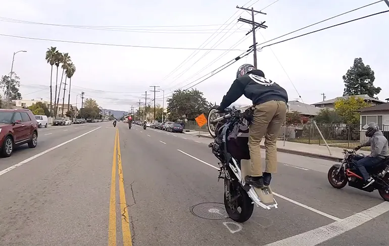 Stuntende waaghals op motor maakt schuiver op het asfalt