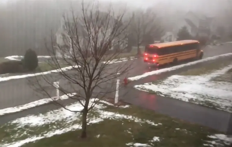 Volle schoolbus glijdt naar beneden op zeer gladde weg