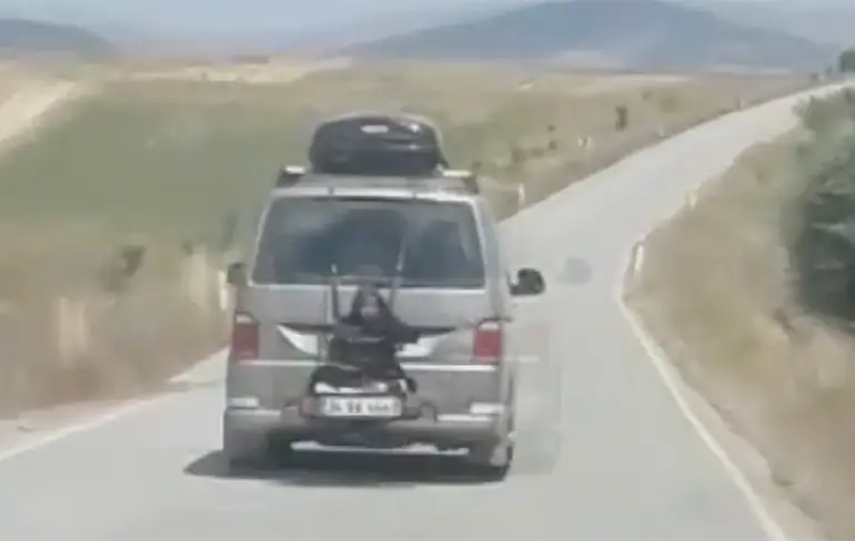 Vrouw rijdt achterop busje mee in Turkije