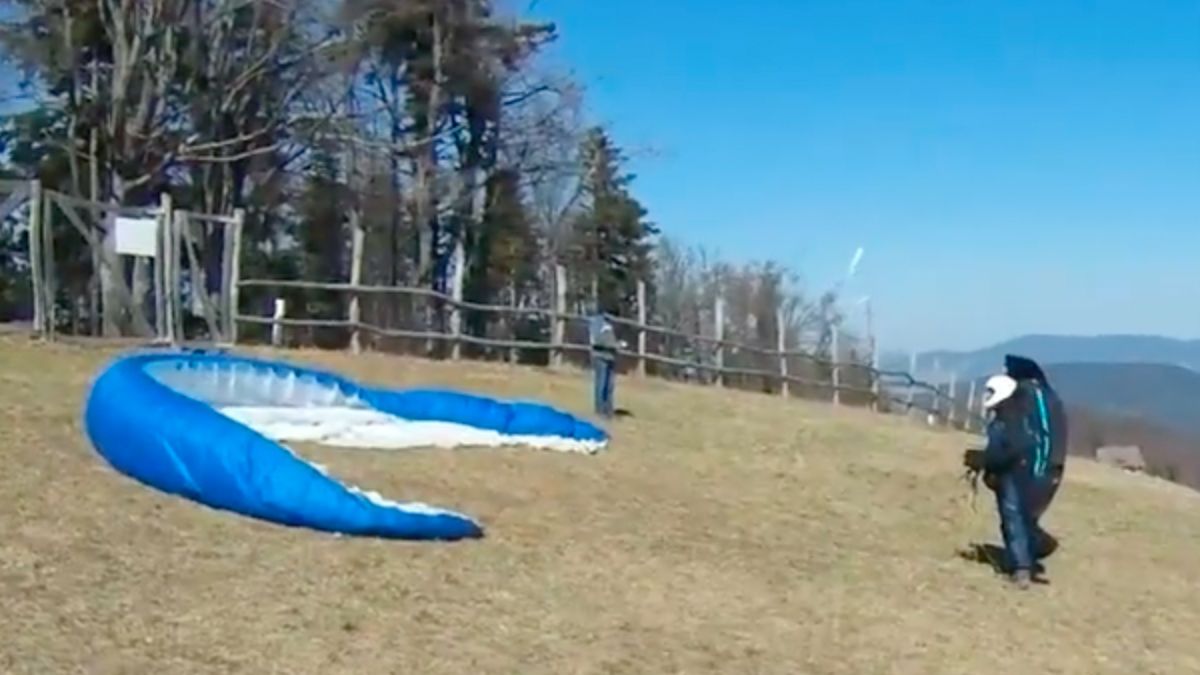 Windhoos slingert paraglider de bomen in
