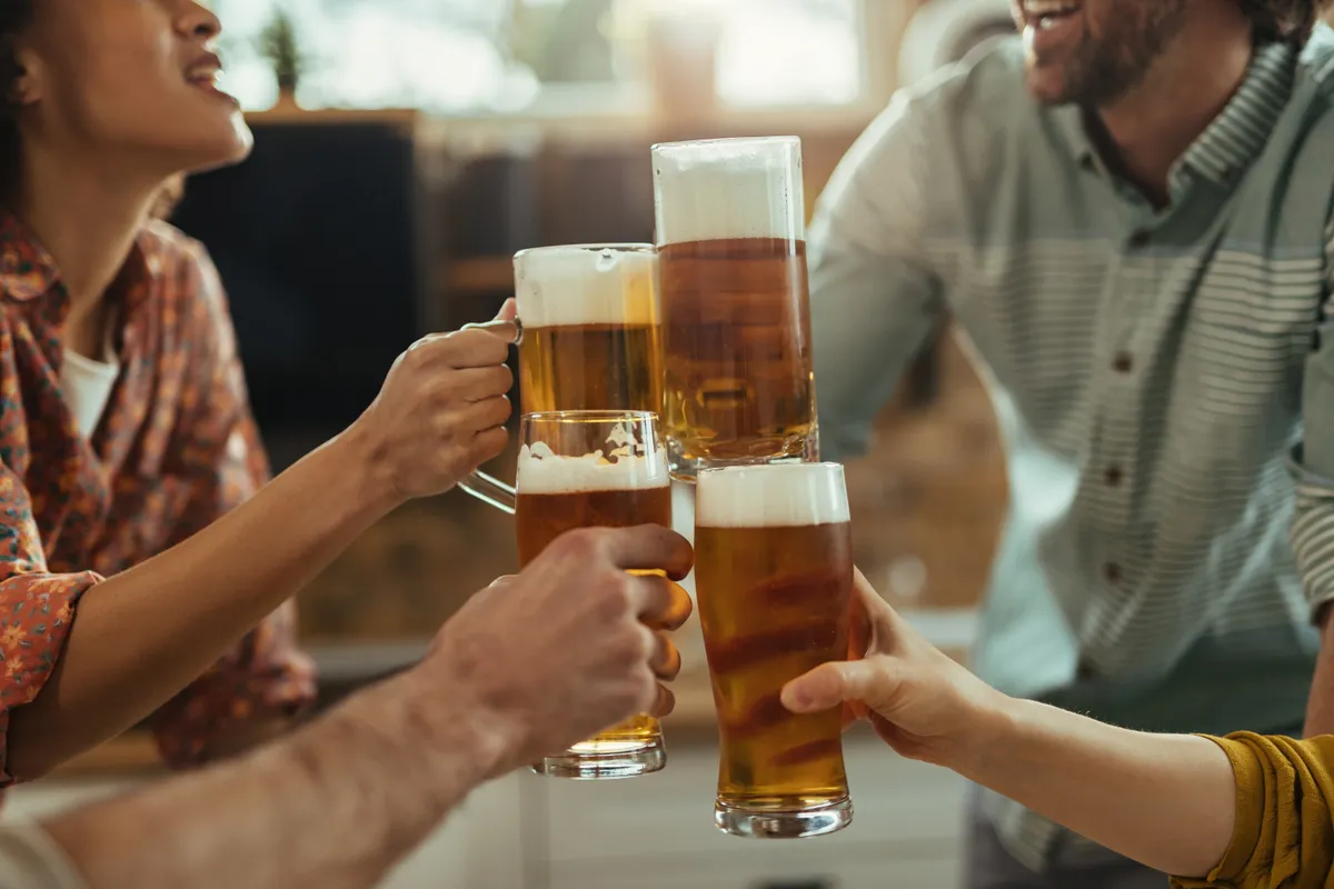 close up group people toasting with beer home party