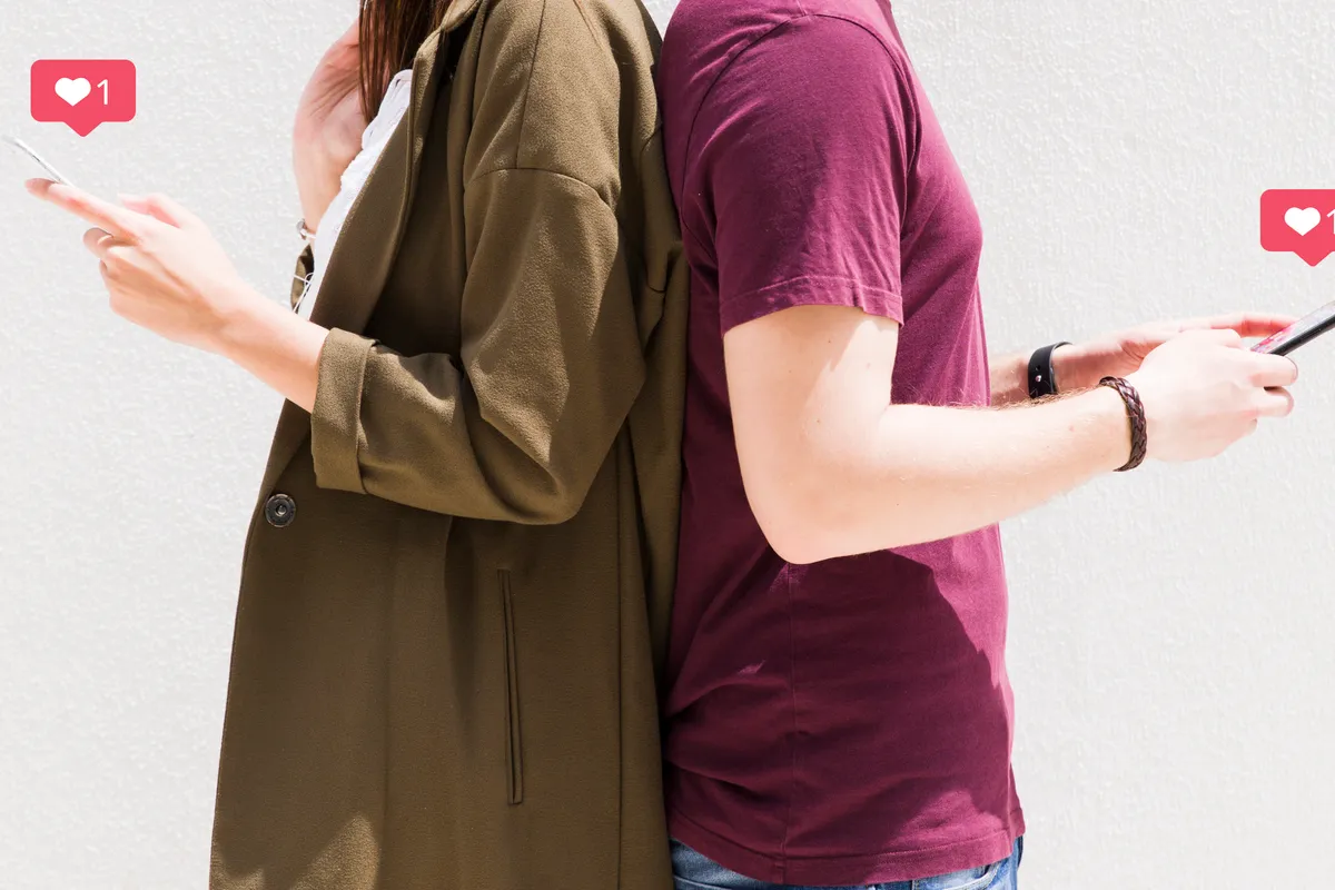 couple standing back back using cellphone with love messages icons against wall