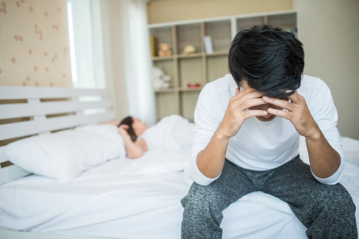 upset man having problem sitting bed after arguing with his girlfriend