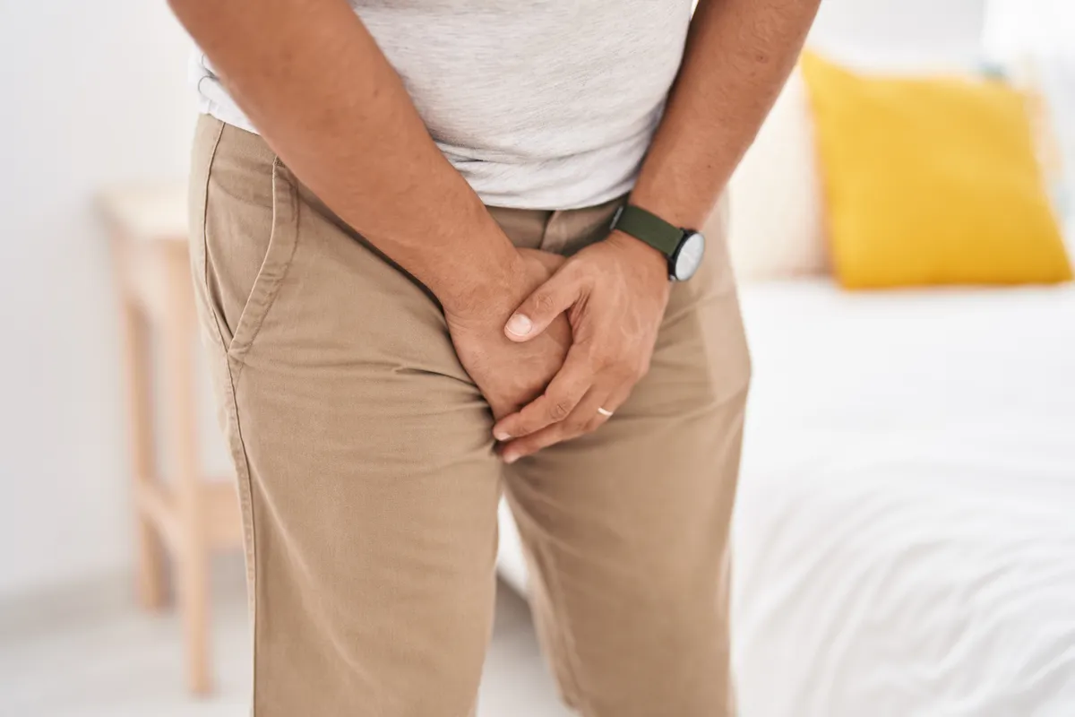 young latin man covering his genitals with hands bedroom