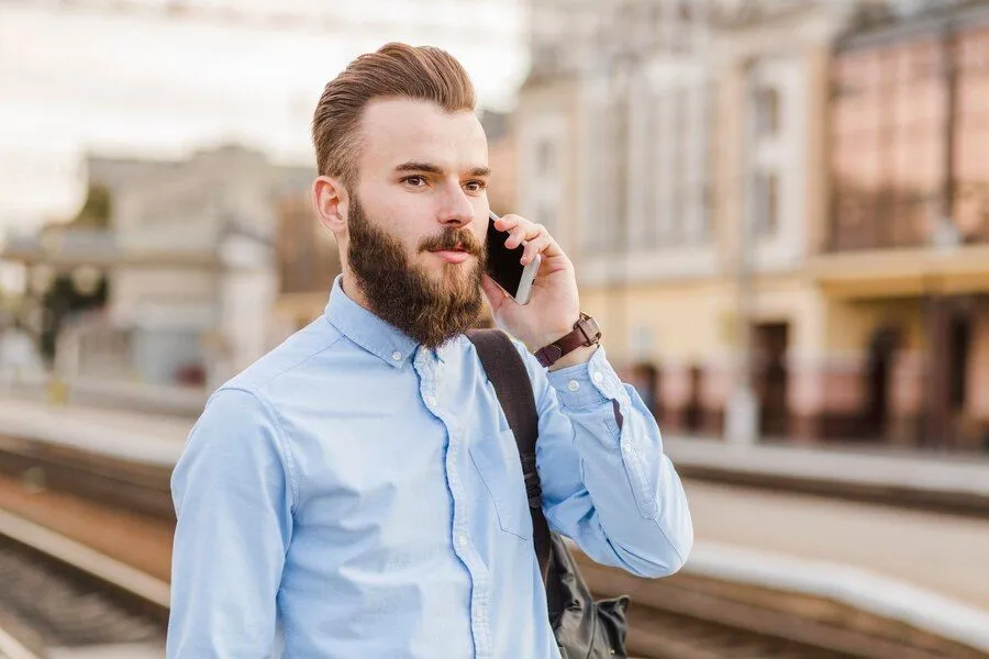 close up bearded young man using mobile phone railway station 23 2147955352