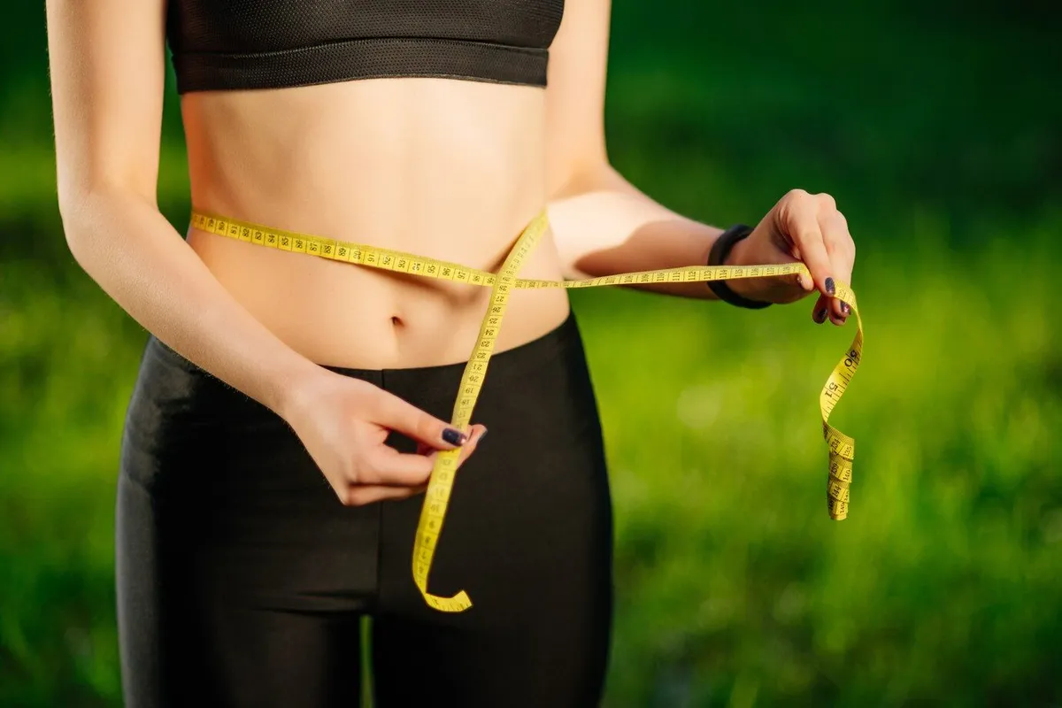 young woman measuring her thin waist with tape measure 8353 5995