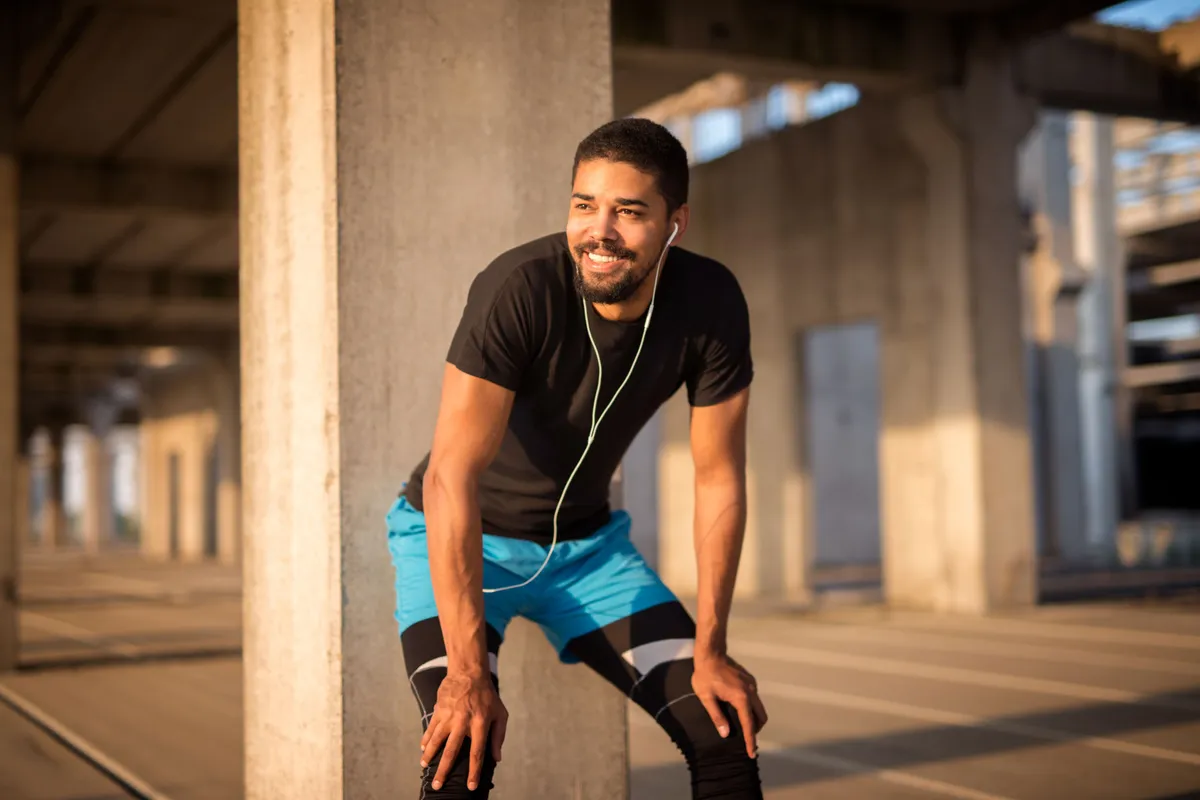 sporty attractive male listening music smiling training