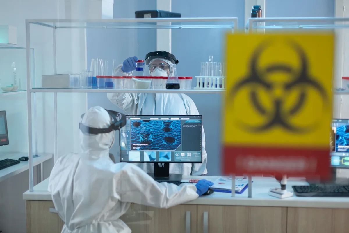 biologist researchers team wearing protective medical equipment against coronavirus while developing covid19 vaccine working microbiological hospital laboratory danger sign glass