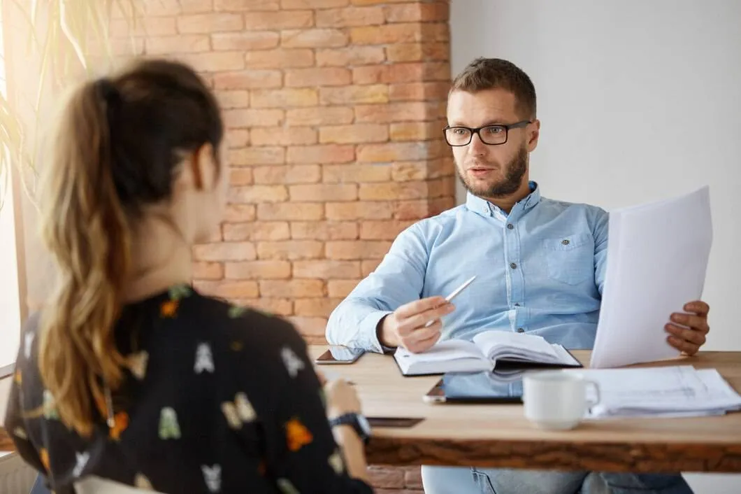 business concept mature bearded serious male company director sitting office front dark haired girl who came job interview looking through papers talking about work experience 176420 8662