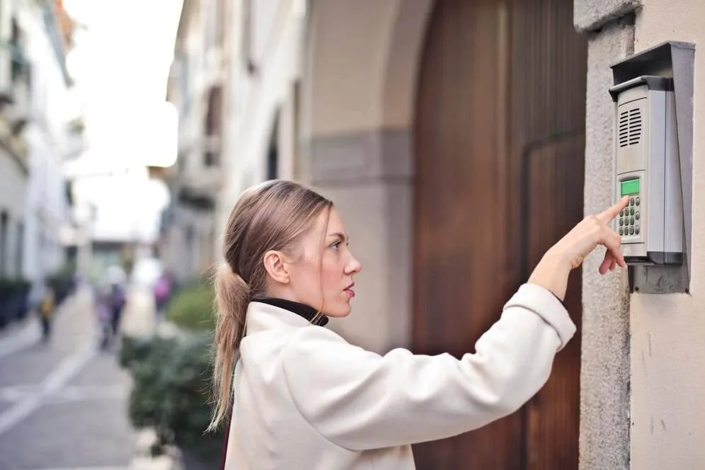 young woman presses button intercom 641386 184