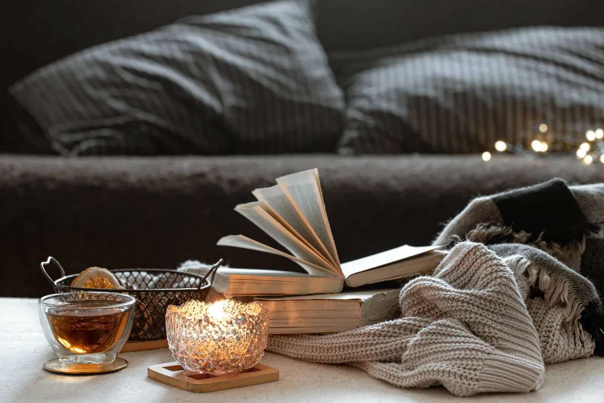 still-life-with-cup-tea-books-burning-candle-beautiful-candlestick-home-comfort-concept