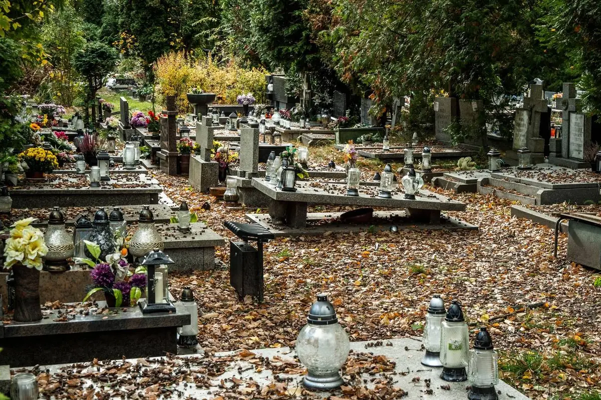 Begraafplaats in de herfst met afgevallen bladeren, bloemen en grafkaarsen op de graven