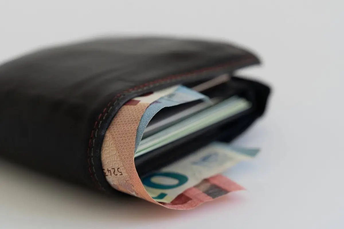 Zwarte portefeuille vol eurobiljetten op een witte ondergrond