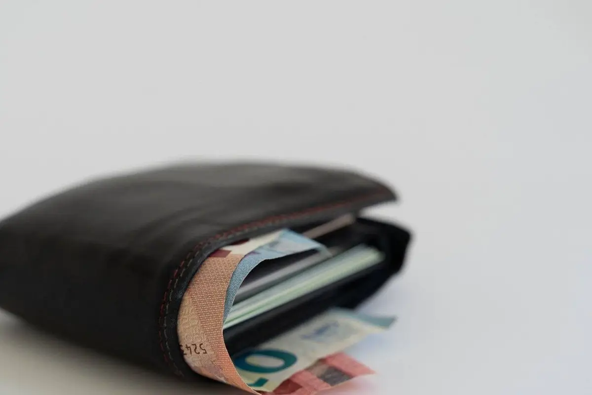 Zwarte lederen portefeuille met eurobiljetten van 10 en 20 euro op een witte achtergrond