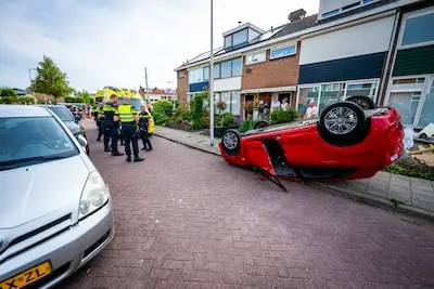 Bestuurder wordt onwel, botst tegen geparkeerde auto en slaat over de kop