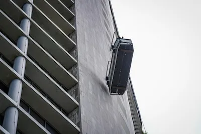 Bakje van glazenwasser waait op grote hoogte van links naar rechts naast bekende toren in Eindhoven