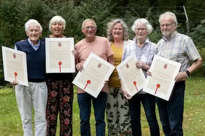 Vrijwilligers van werkgroep wijkblad Rond ‘t Hofke ontvangen oorkonde van wethouder Verhees.