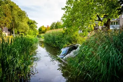 Auto rijdt een sloot in Alphen in, voorkant verdwijnt onder water