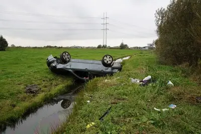 Auto hangt op zijn kop boven sloot langs de N446 bij Hoogmade
