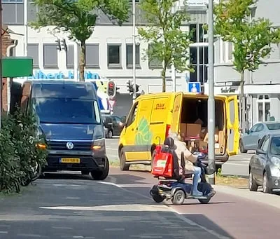 Scheurende bestelbus over de stoep en een dikke vinger van de pakketkoerier