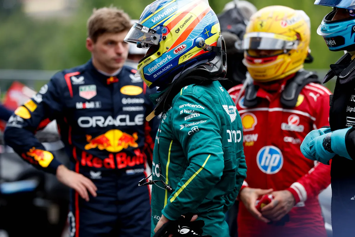 Aston Martin-coureur Fernando Alonso in de pitstraat in België, met Max Verstappen en Lewis Hamilton op de achtergrond