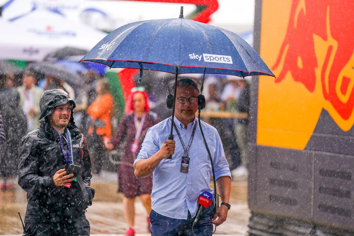 Sky Sports-verslaggever Ted Kravitz loopt in de regen voor de motorhome van Red Bull Racing
