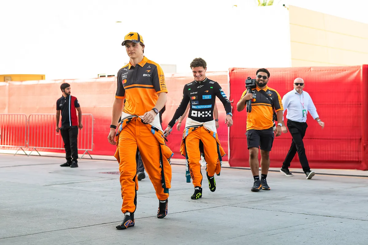 Oscar Piastri wordt achtervolgd door een lachende Lando Norris in de paddock in Bahrein