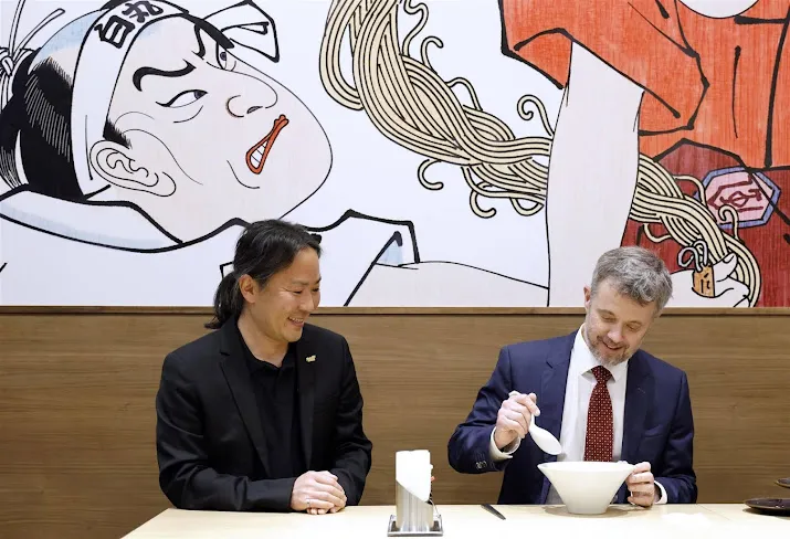 Koning Frederik eet ramen en poseert met pluizige robot in Japan