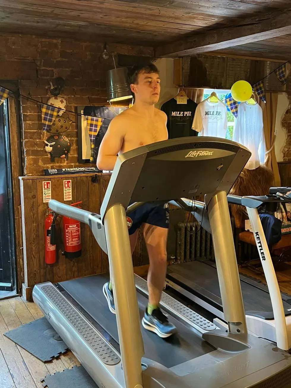 a-shirtless-man-running-on-a-treadmill-in-a-pub
