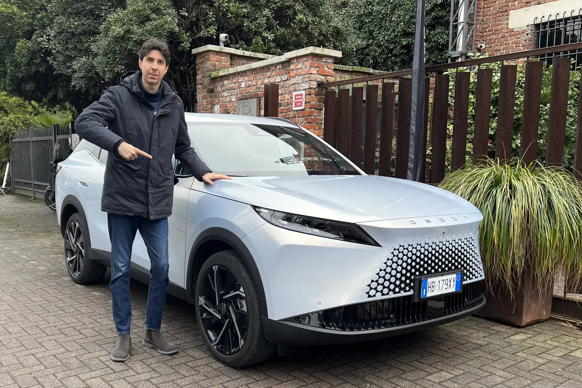 Omoda 7 SHS-P plug-in super ibrida vista frontalmente con una persona accanto