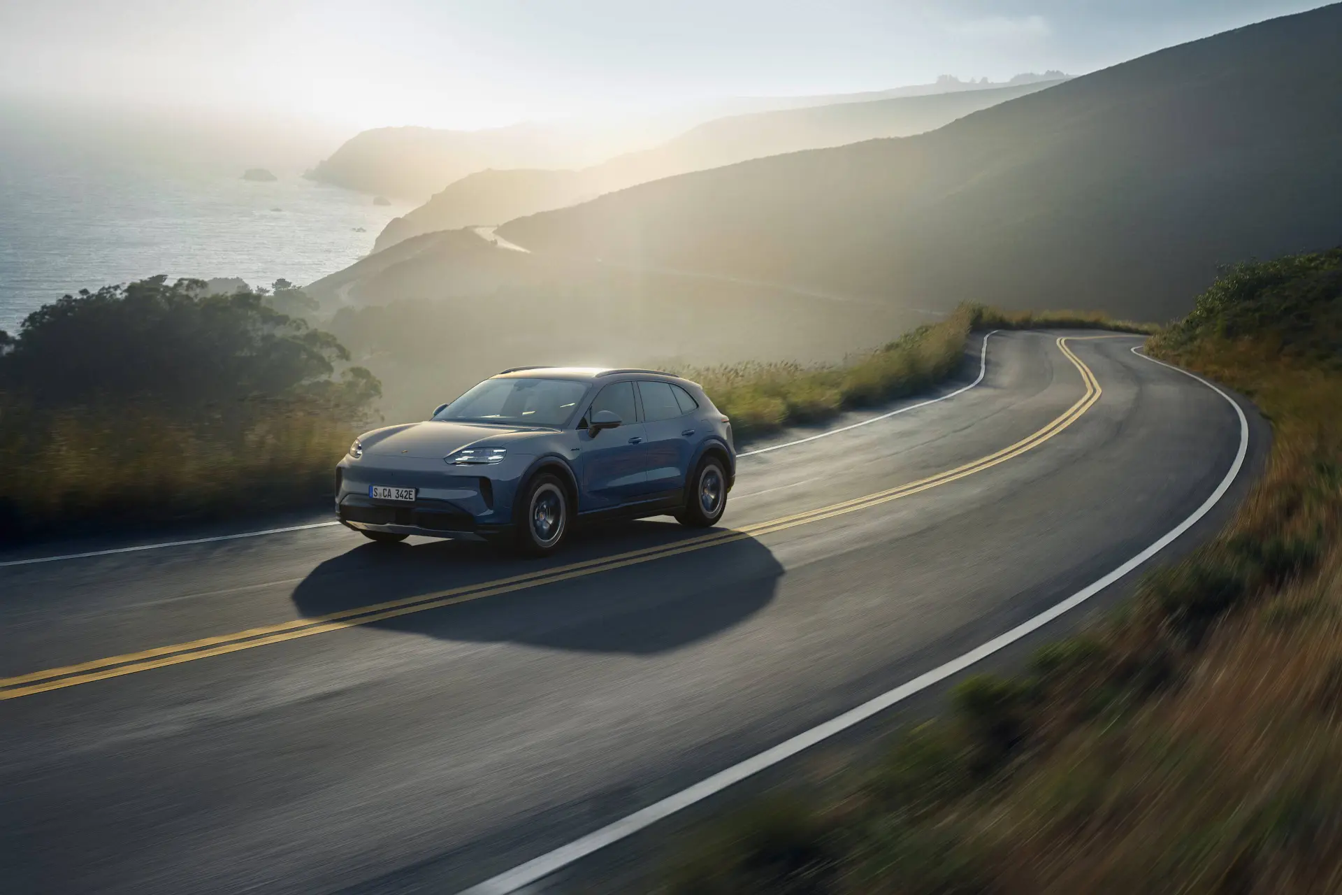 Porsche Cayenne S elettrico dinamica di colore grigio con sfondo mare e tramonto