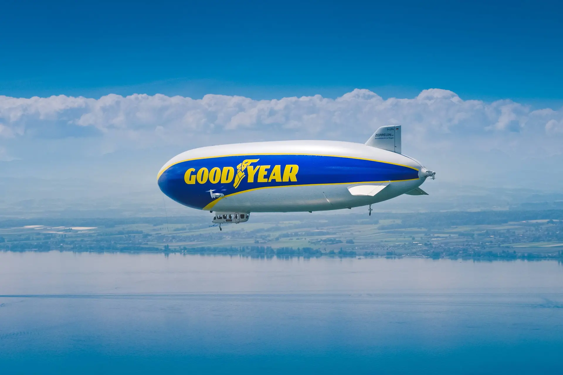 Dirigibile Goodyear che vola nei cieli sopra a un grande specchio d'acqua