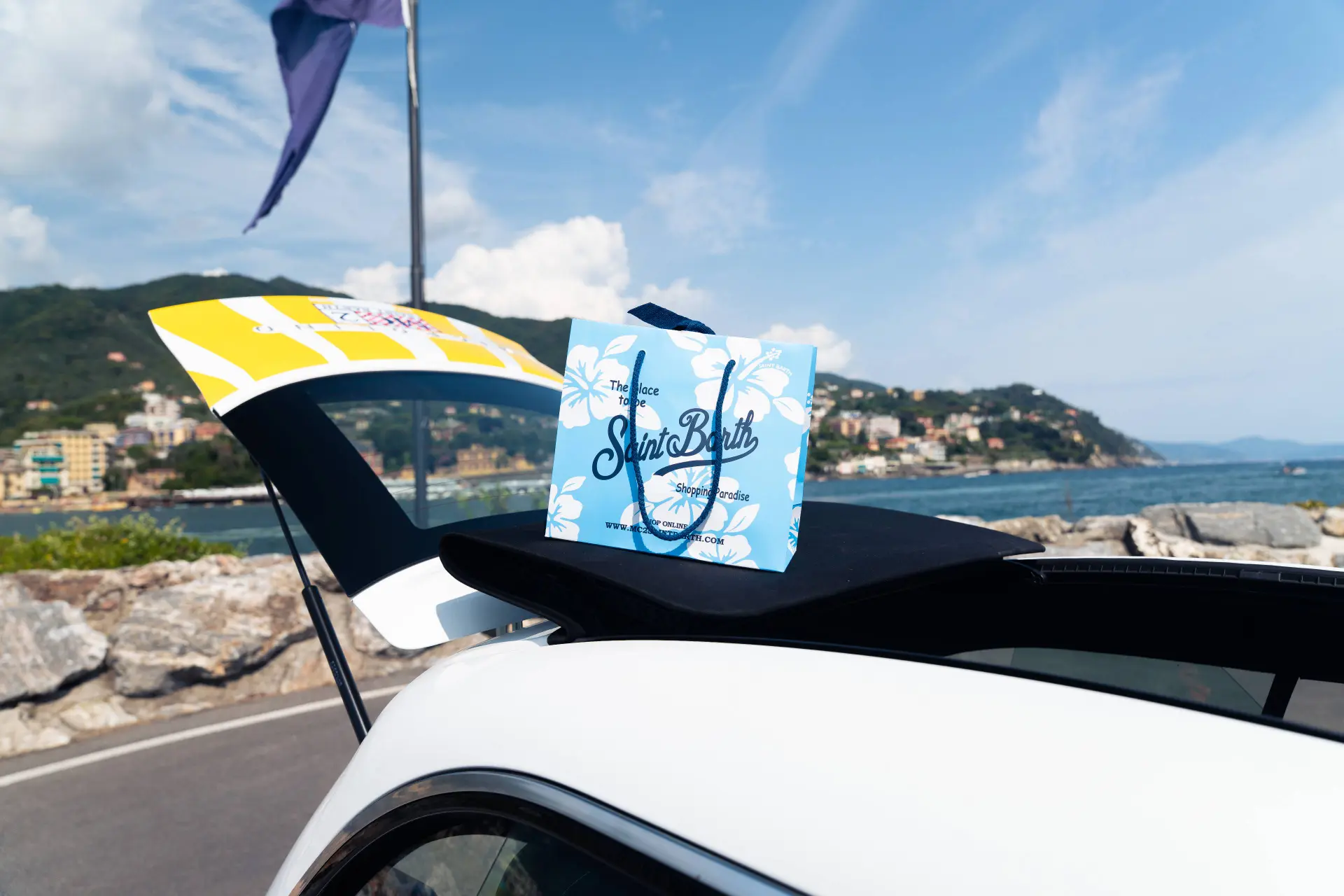 Nell'immagine si vede il tettuccio della Microlino brandizzata MC2 Saint Barthes con sopra il sacchetto della boutique del negozio di Portofino