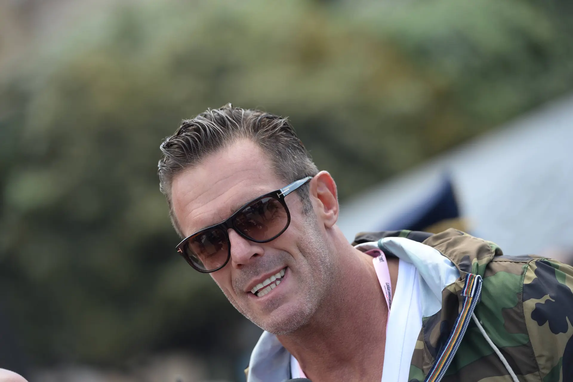 Mario Cipollini, vestido de calle con unas gafas de sol y sonriendo